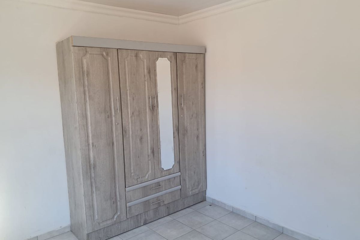 A simple bedroom featuring tiled flooring and classic ceiling cornicing, providing a clean and neutral space ready for personalization.
