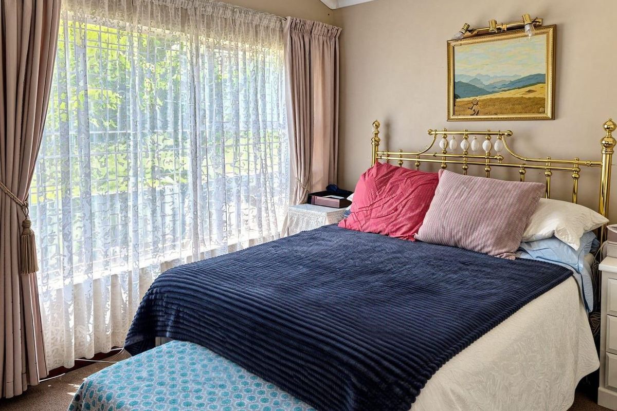A cozy bedroom featuring a large window with natural light, neutral wall tones, and coved ceiling detailing.