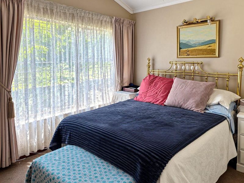 A cozy bedroom featuring a large window with natural light, neutral wall tones, and coved ceiling detailing.