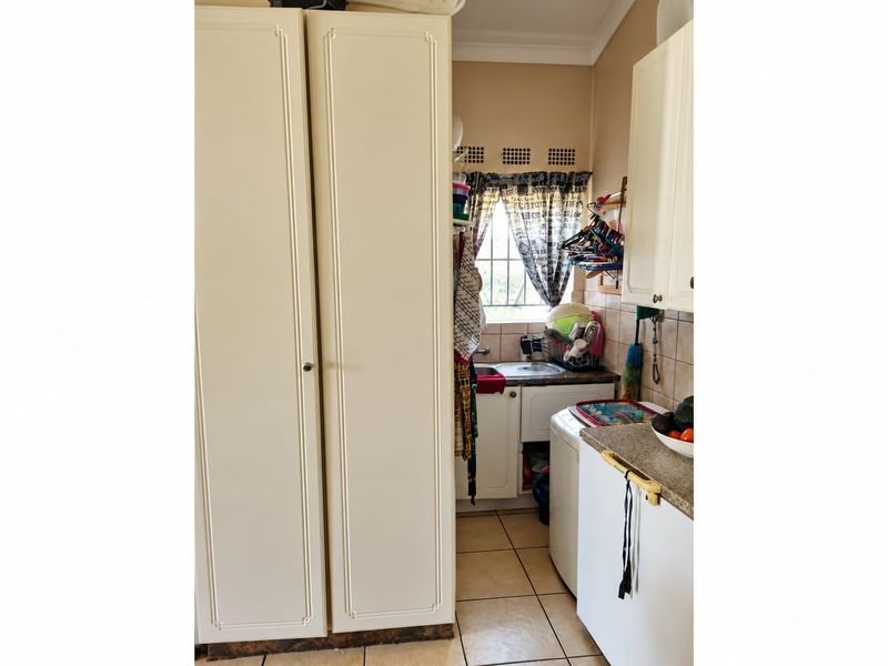 A functional laundry area featuring built-in cabinetry, tiled flooring, and a tiled backsplash, providing practical utility space within the townhouse.