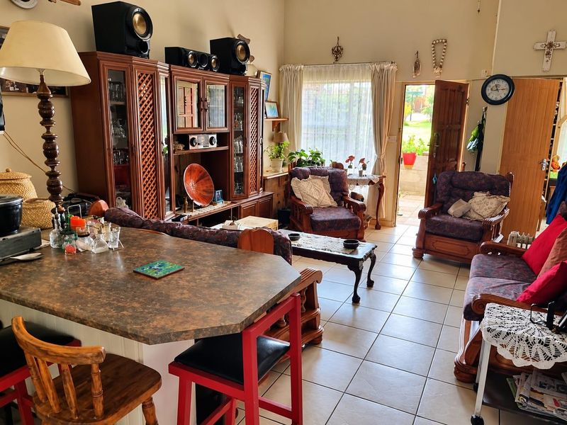 Open-plan living area featuring tiled flooring, a kitchen island, and direct access to an outdoor patio space.