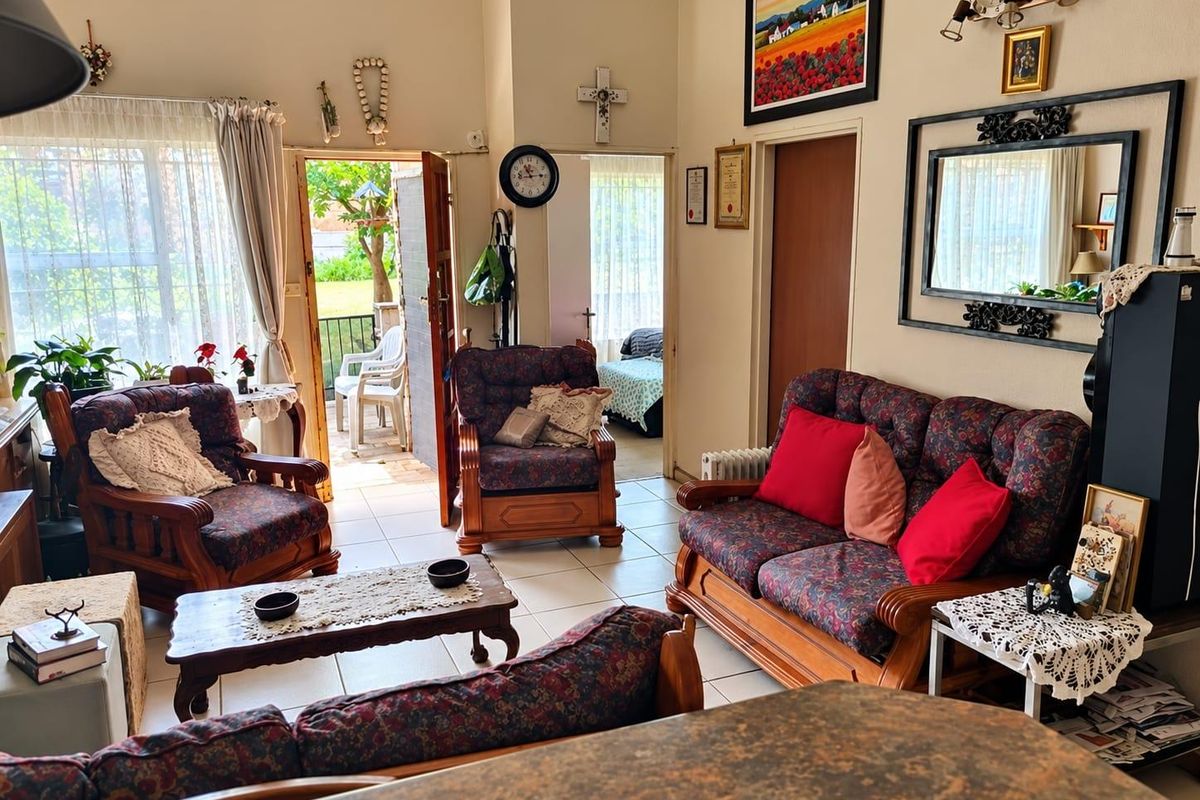 A spacious living room featuring tiled flooring and direct access to an outdoor patio area through a sliding glass door.