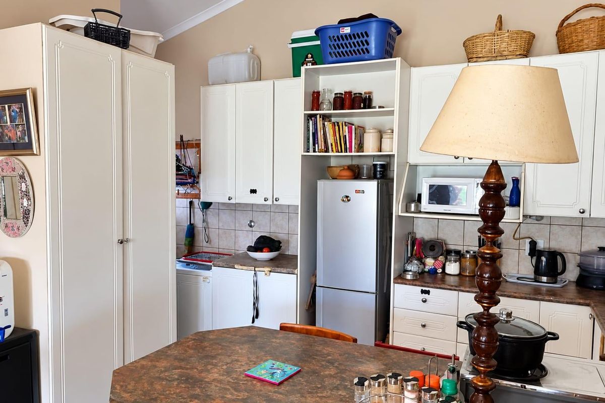 A functional kitchen featuring white cabinetry, tiled backsplash, laminate countertops, and a vaulted ceiling, providing a practical layout for daily meal preparation.