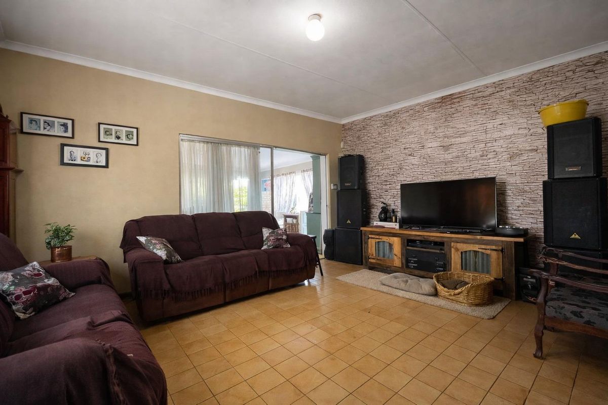 A living room featuring tiled flooring, a textured stone-look feature wall, and sliding glass doors providing access to an outdoor area.
