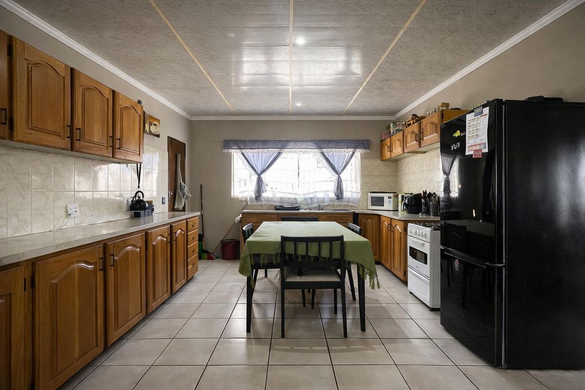 Spacious kitchen featuring wooden cabinetry, tiled flooring, and a dedicated dining area, offering a functional layout with ample storage space.