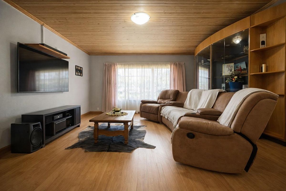 A comfortable living room featuring wood-paneled ceilings, laminate flooring, and a large built-in display cabinet with glass shelving.
