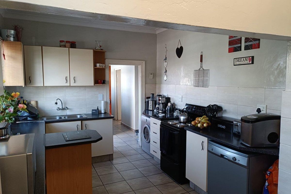 Functional kitchen featuring tiled flooring, ample built-in cabinetry, laminate countertops, and a tiled backsplash, providing a practical workspace for daily meal preparation.