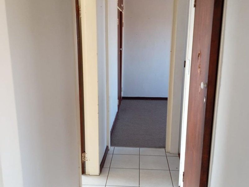 A functional hallway featuring tiled flooring and wooden doors, connecting various rooms within the apartment.