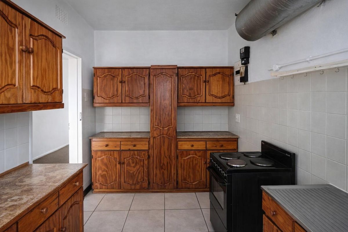 A functional kitchen featuring traditional wooden cabinetry, tiled backsplash, and a freestanding electric stove, offering a classic layout ready for modern updates.