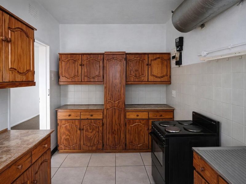 A functional kitchen featuring traditional wooden cabinetry, tiled backsplash, and a freestanding electric stove, offering a classic layout ready for modern updates.