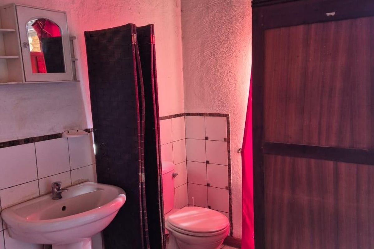 A functional bathroom featuring a pedestal washbasin, toilet, and tiled finishes, requiring cosmetic updates to modernize the space.