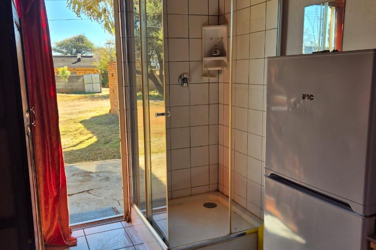 A compact bathroom featuring a shower enclosure with tiled walls and flooring, providing direct access to the outdoor area.