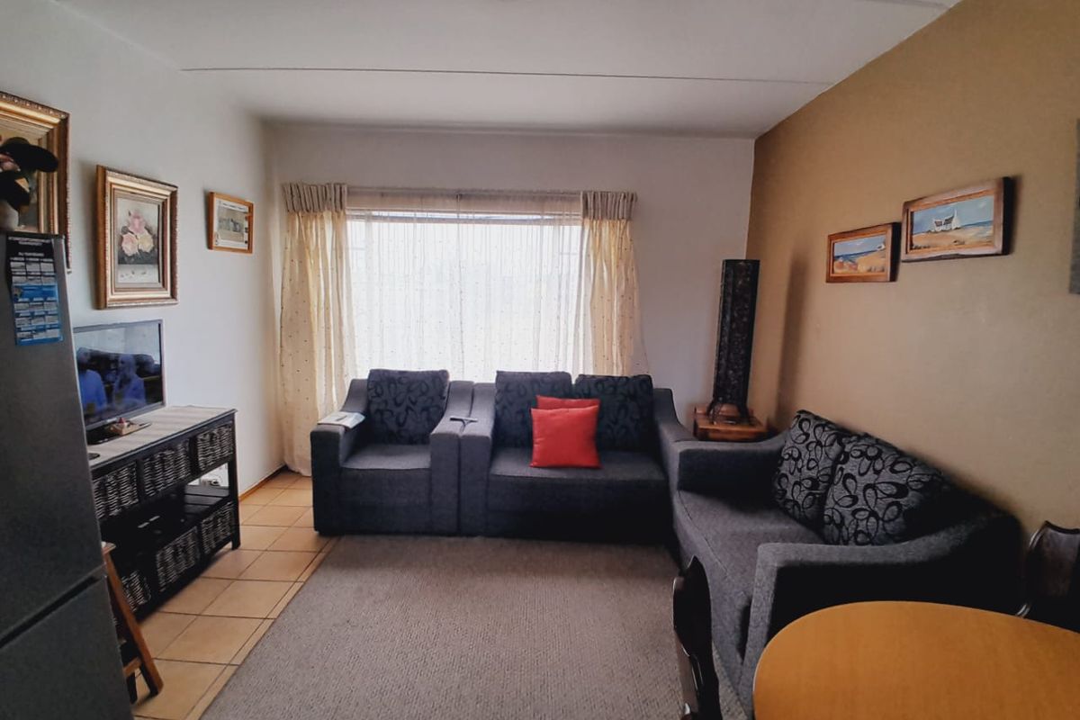 A living room area featuring tiled flooring, a large window with curtains, and neutral wall finishes.
