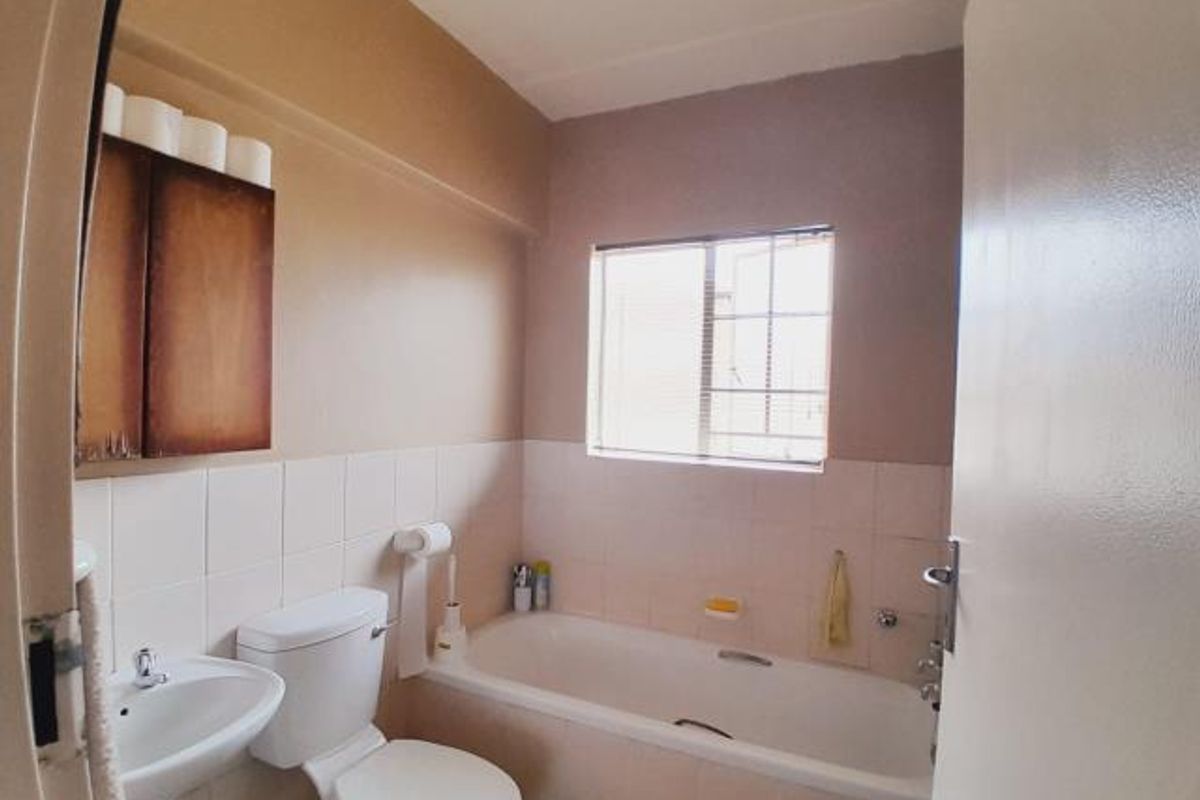 A functional bathroom featuring a standard bathtub, pedestal basin, and toilet, finished with neutral wall tiles and painted walls.