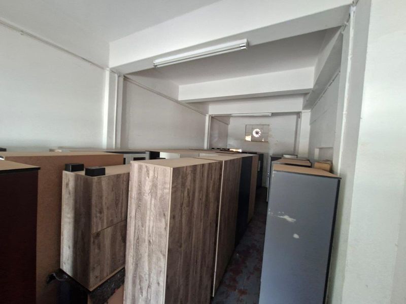 A functional utility or storage space featuring industrial lighting and an exhaust fan, suitable for various commercial storage or operational needs.