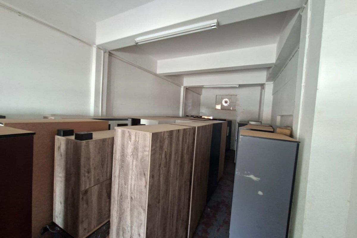 A functional utility or storage space featuring industrial lighting and an exhaust fan, suitable for various commercial storage or operational needs.