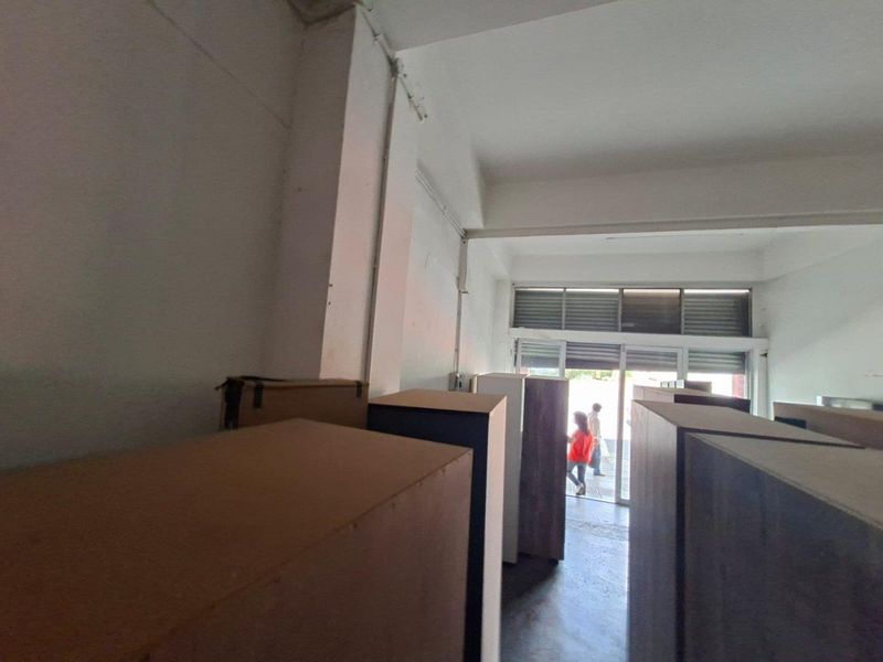 Open plan commercial space featuring concrete flooring, exposed ceiling beams, and large aluminium framed glass sliding doors providing natural light and street access.