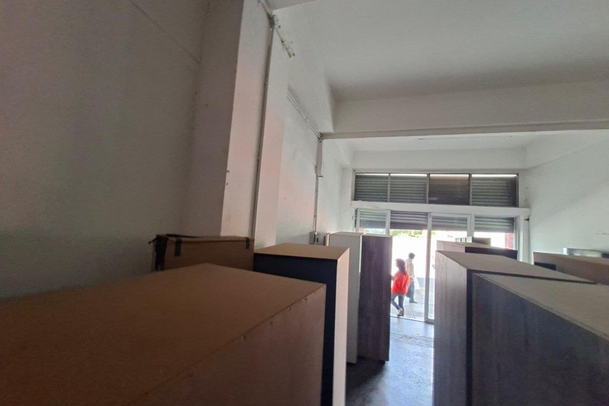 Open plan commercial space featuring concrete flooring, exposed ceiling beams, and large aluminium framed glass sliding doors providing natural light and street access.