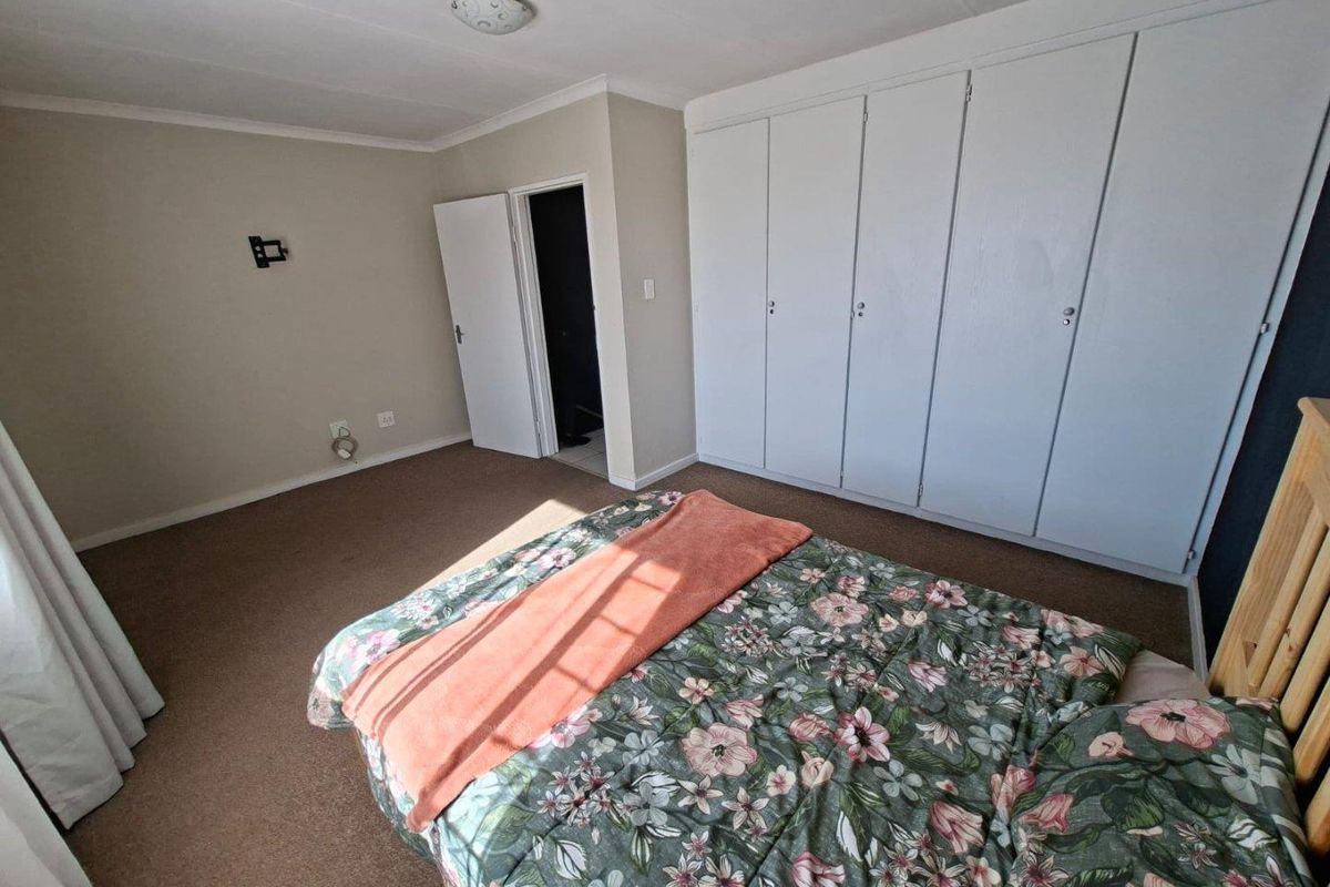 A bedroom featuring built-in cupboards and neutral wall finishes, providing a functional space with standard fixtures.