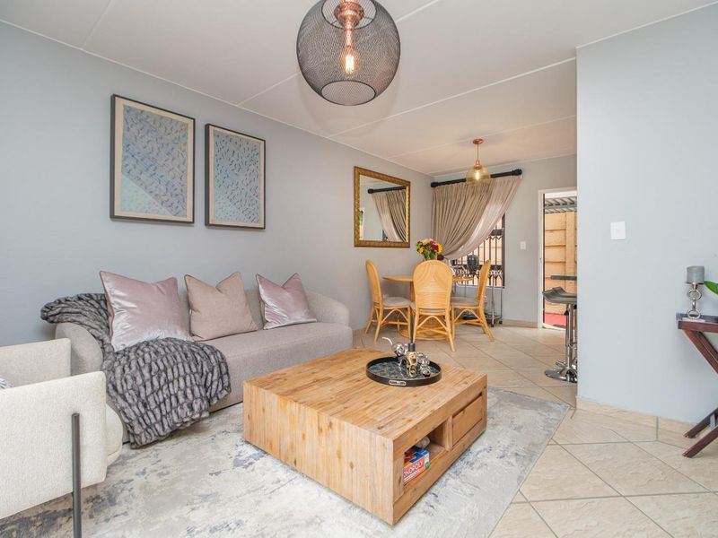 An open-plan living and dining area featuring tiled flooring, neutral wall tones, and direct access to an outdoor patio space.