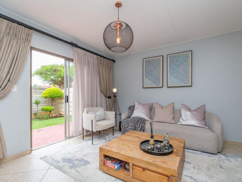 A bright living room featuring tiled flooring and large sliding glass doors that provide direct access to a private garden patio.
