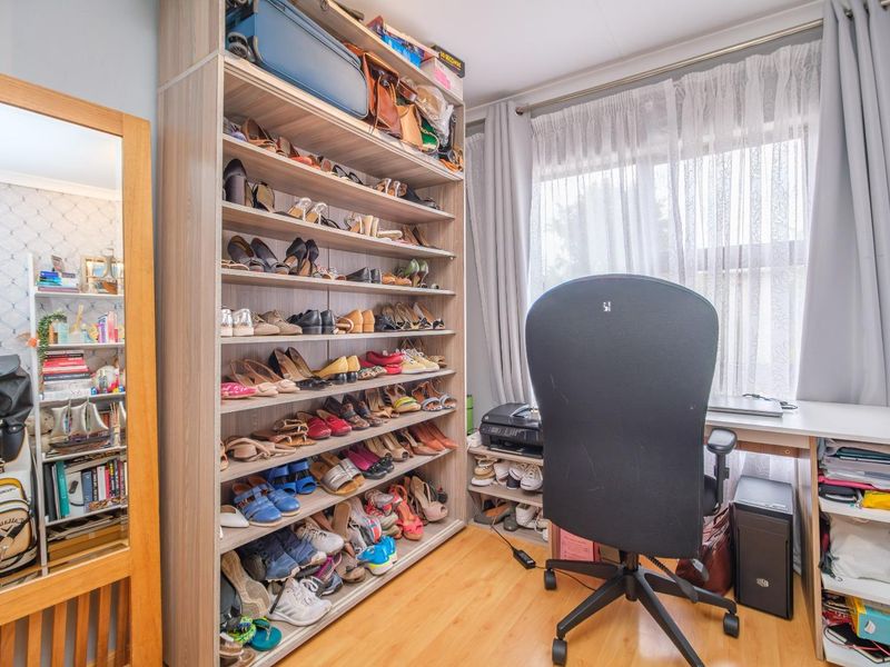 A functional home office or study space featuring laminate flooring and a large built-in shelving unit for storage.