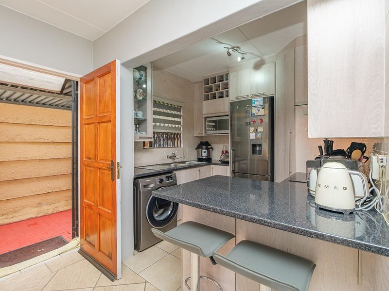 Compact kitchen featuring granite countertops, built-in cabinetry, integrated appliance space, and direct access to an outdoor area.