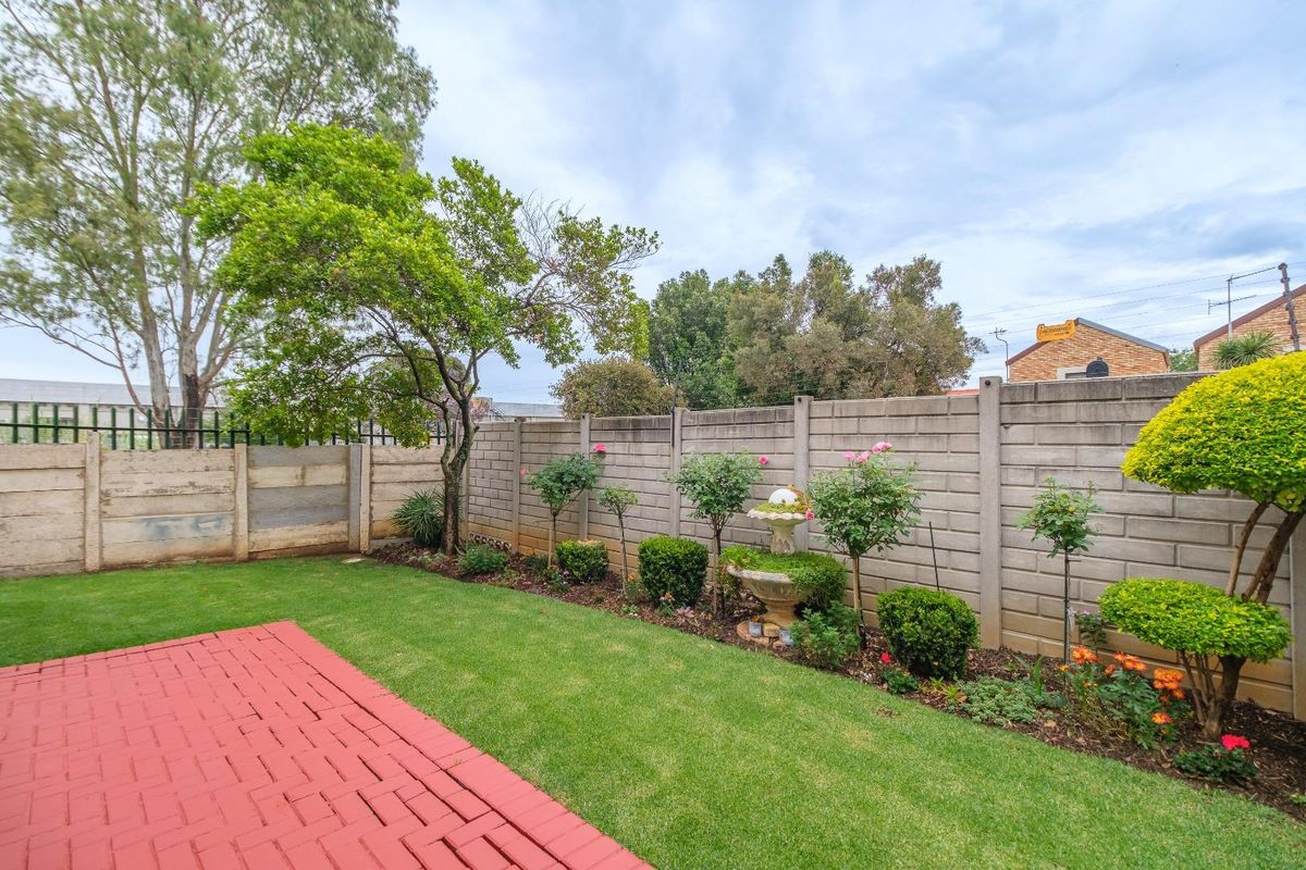 A private rear garden featuring a paved patio area, manicured lawn, and established perimeter walling.
