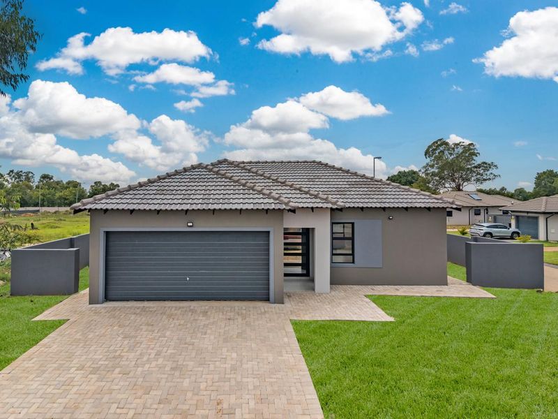 Modern single-story residential home featuring a tiled roof, automated garage, paved driveway, and well-maintained lawn in a suburban setting.