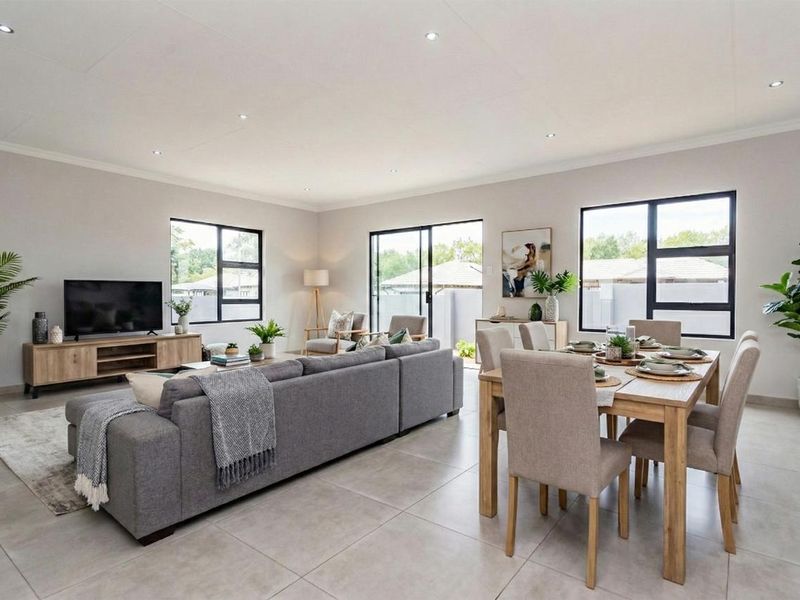 Spacious open-plan living and dining area featuring modern tiled flooring, recessed downlights, and large windows providing ample natural light.