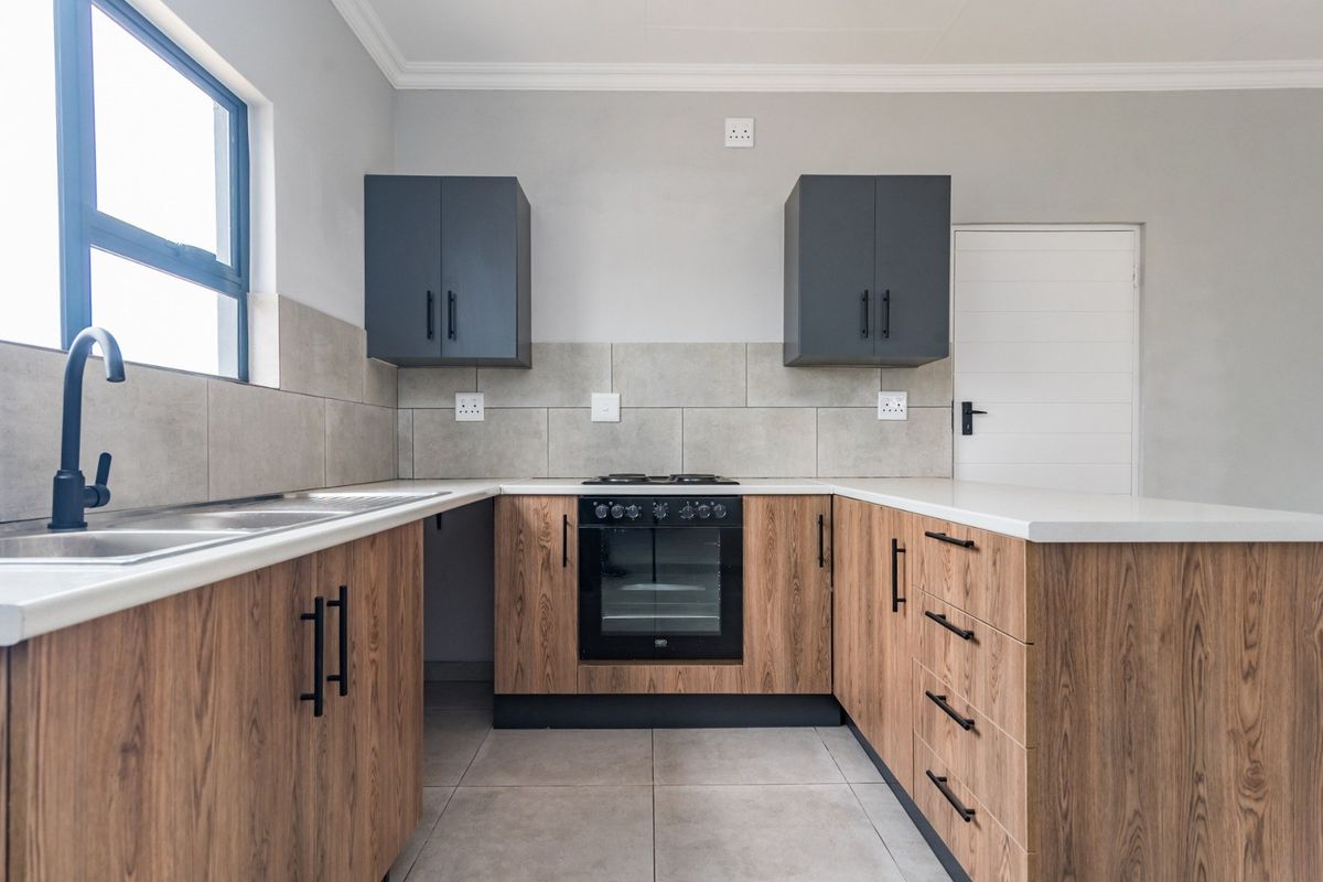 Modern kitchen featuring wood-grain cabinetry, stone countertops, built-in oven with gas hob, and neutral tiled finishes in a clean, contemporary layout.