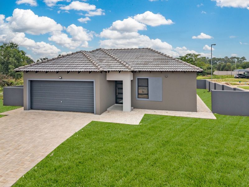 A modern single-story residential home featuring a tiled roof, automated garage, paved driveway, and well-maintained lawn in a secure estate setting.