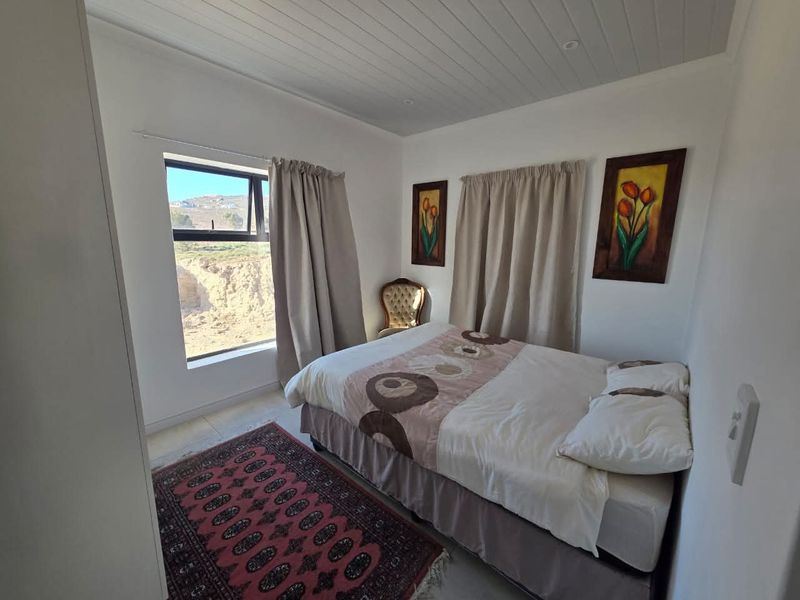 A bright bedroom featuring a tongue-and-groove ceiling, large window with natural light, and neutral wall finishes.