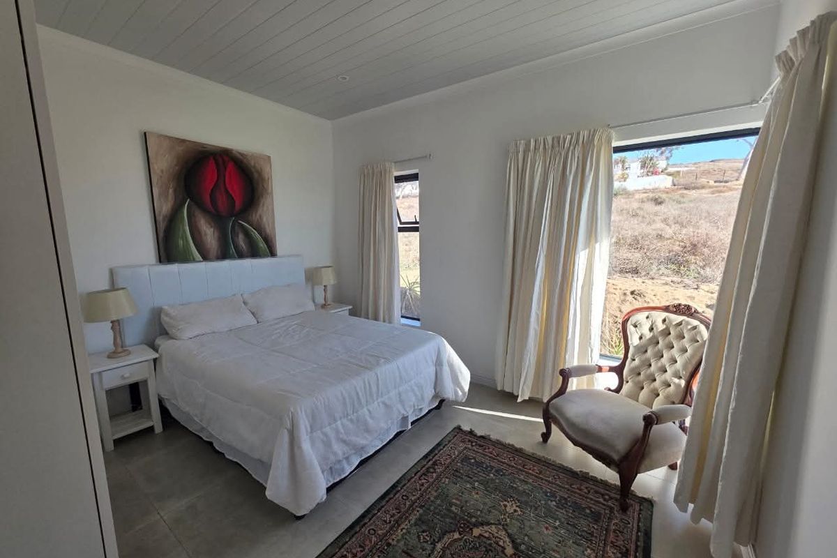 A bright bedroom featuring tiled flooring, a white paneled ceiling, and large windows providing natural light and scenic views.