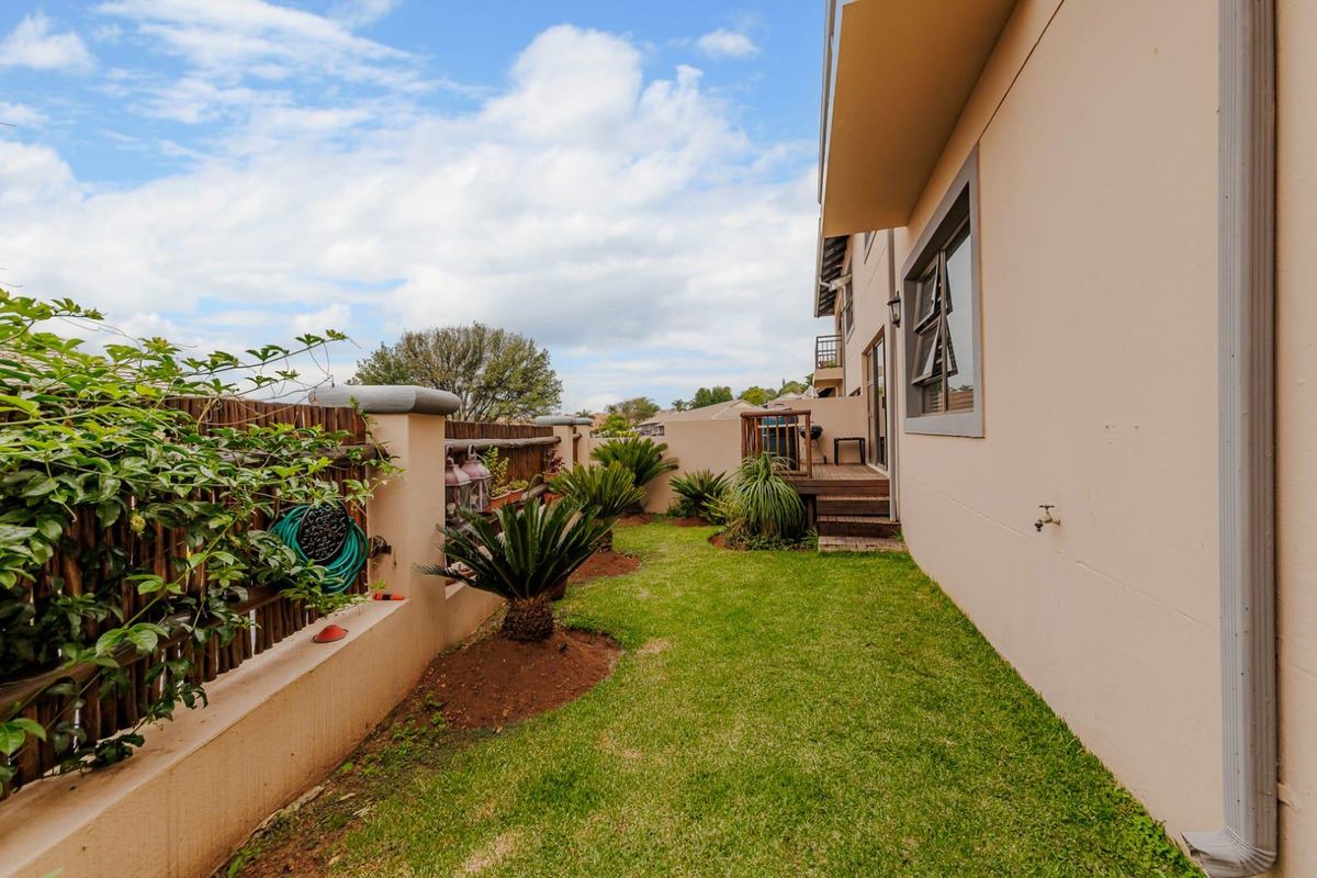 A well-maintained rear garden area featuring a small timber deck, lawn, and boundary wall with integrated landscaping.