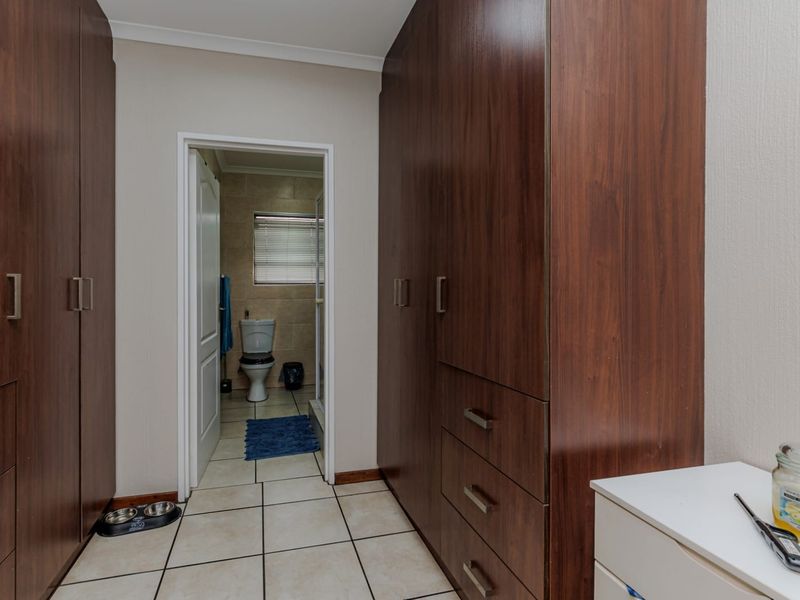 A hallway featuring extensive built-in wooden cabinetry and tiled flooring, providing direct access to an adjoining bathroom.