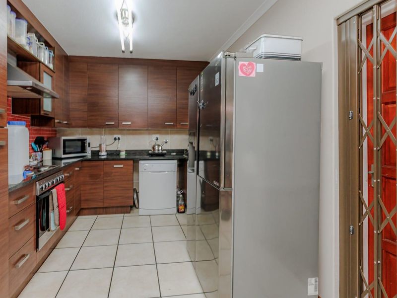 A functional kitchen featuring dark wood cabinetry, granite countertops, tiled flooring, and a built-in oven with an extractor fan.