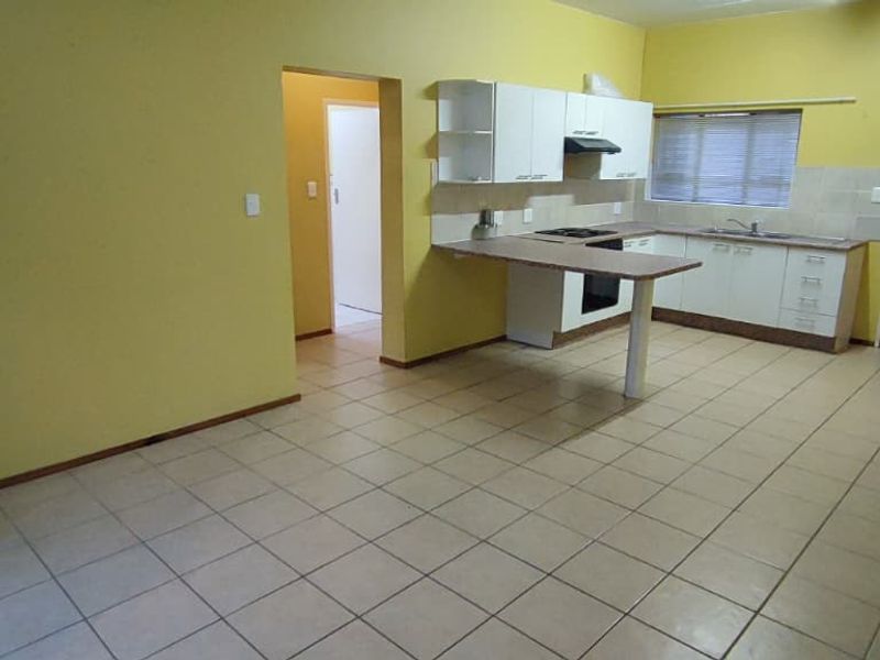 Open-plan kitchen and living area featuring tiled flooring, built-in cabinetry with a breakfast bar, and a functional layout.