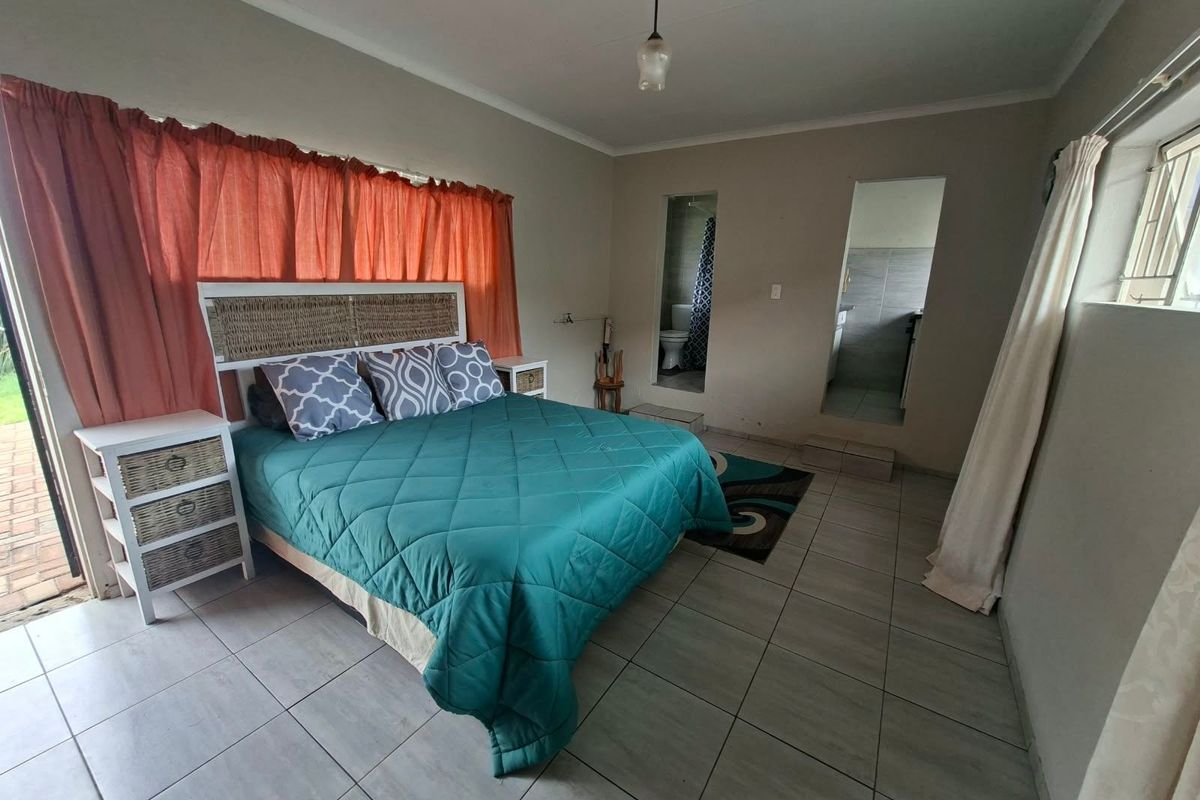 A bedroom featuring tiled flooring, direct access to an en-suite bathroom, and a sliding door leading to the exterior.