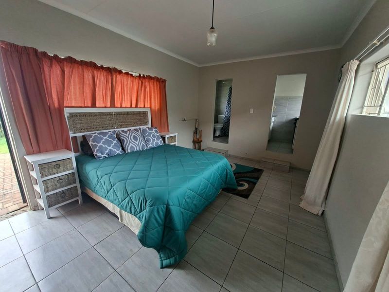 A bedroom featuring tiled flooring, direct access to an en-suite bathroom, and a sliding door leading to the exterior.