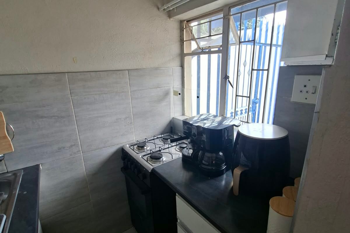 Compact kitchen featuring a gas stove, tiled splashback, and built-in cabinetry, requiring cosmetic updates to improve its overall aesthetic and functionality.