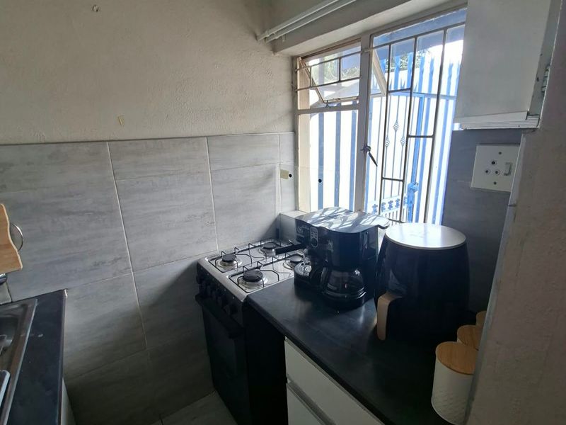 Compact kitchen featuring a gas stove, tiled splashback, and built-in cabinetry, requiring cosmetic updates to improve its overall aesthetic and functionality.
