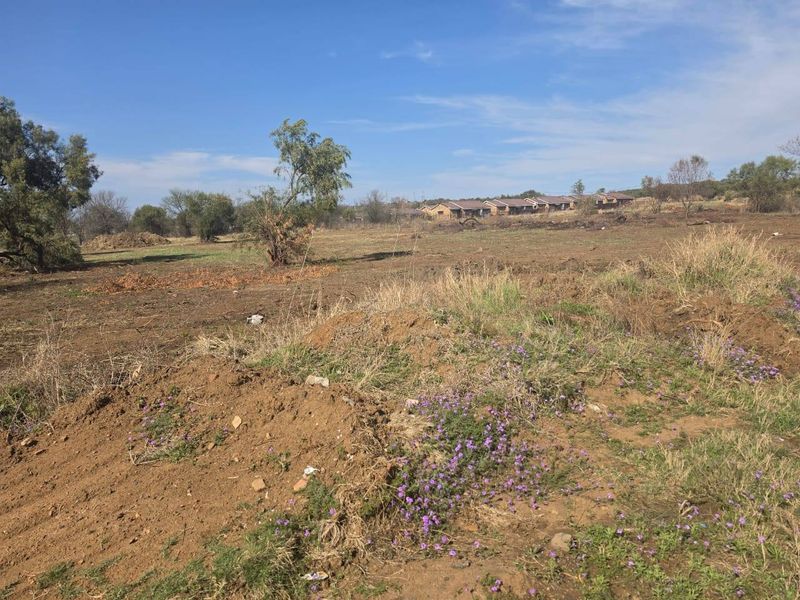 A view of an undeveloped residential plot featuring natural terrain and vegetation, suitable for future construction projects.