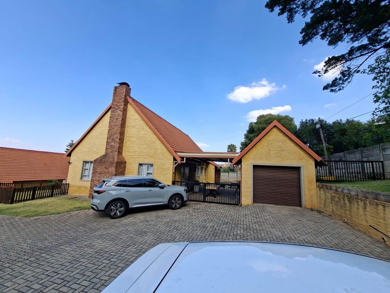 Front exterior view of a yellow brick house featuring a prominent chimney, tiled roof, paved driveway, and an attached single garage.