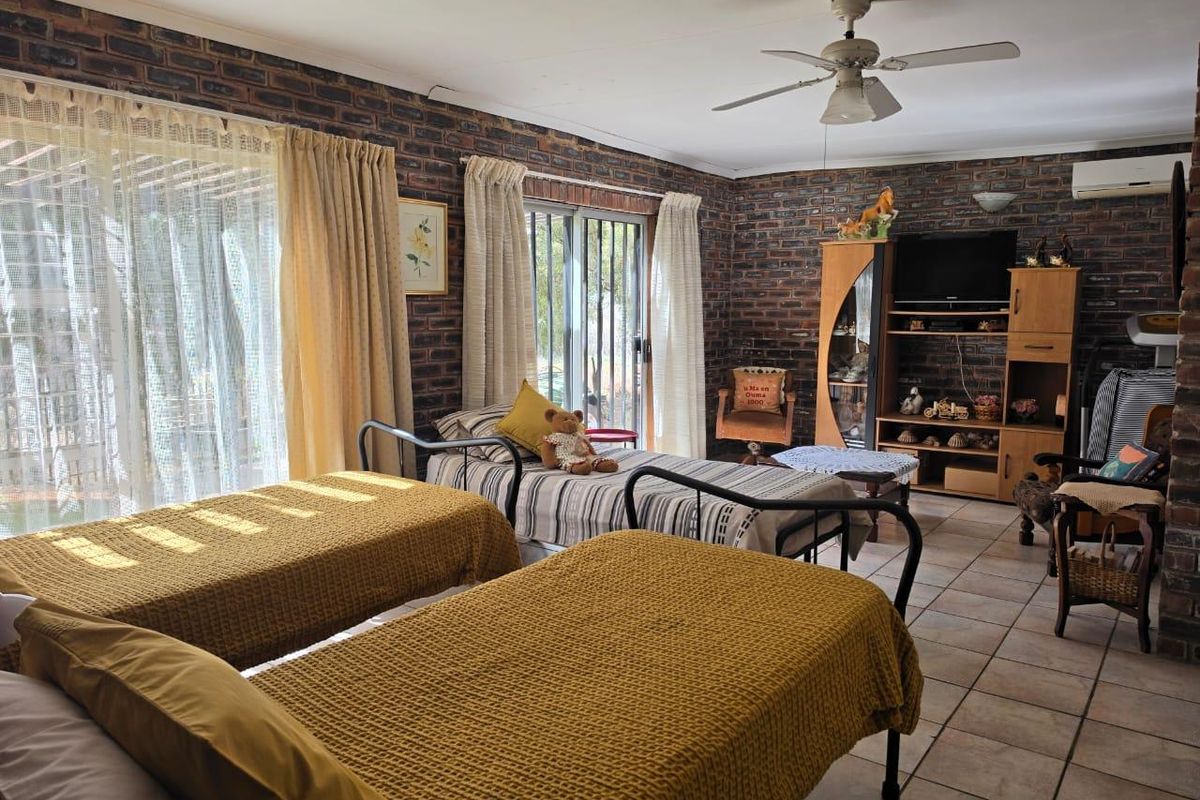 Spacious bedroom featuring exposed brick walls, tiled flooring, a ceiling fan, and sliding glass doors providing access to the exterior.