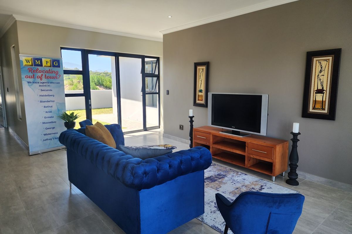 A well-maintained living room featuring tiled flooring, recessed downlighting, and large aluminium sliding doors providing access to the outdoor area.