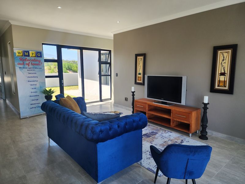 A well-maintained living room featuring tiled flooring, recessed downlighting, and large aluminium sliding doors providing access to the outdoor area.