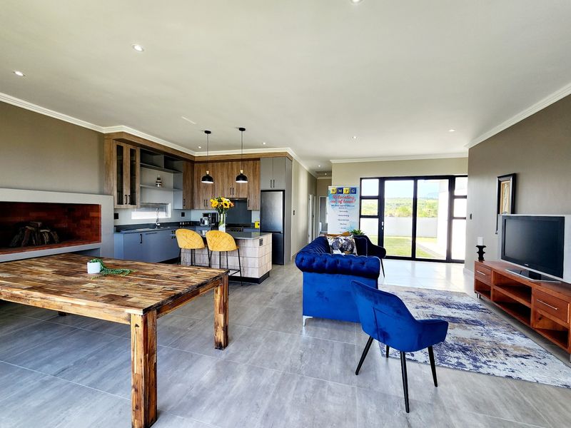 Spacious open-plan living area featuring a modern kitchen with island, built-in fireplace, and large sliding doors leading to the outdoor space.