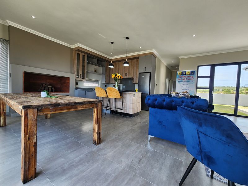 Modern open-plan living area featuring a contemporary kitchen with island, built-in fireplace, and large sliding doors leading to the exterior.
