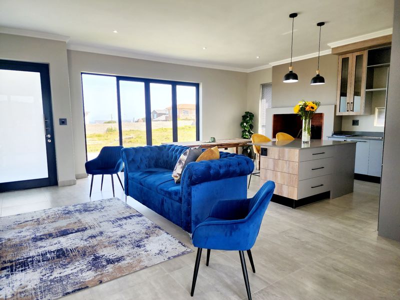 Modern open-plan living area featuring a sleek kitchen island, built-in fireplace, and large sliding glass doors that provide ample natural light.